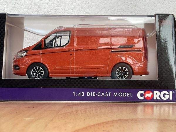 Side view of red Ford Transit die-cast model in packaging
