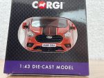 Front of red Ford Transit die-cast model in Corgi packaging