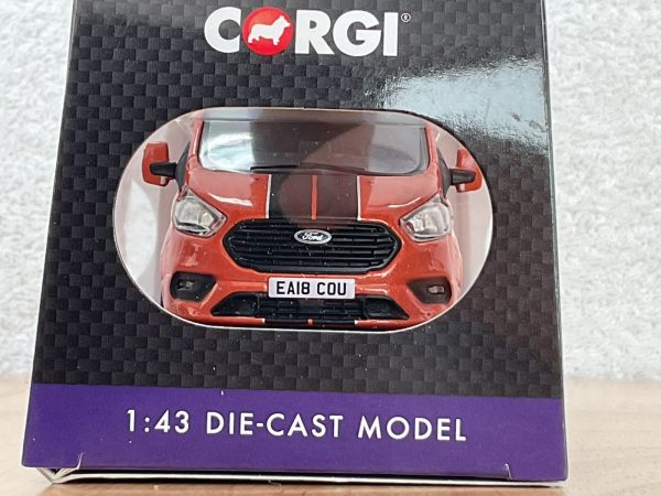 Front of red Ford Transit die-cast model in Corgi packaging